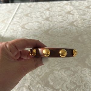 Wooden large bangle bracelet with round  gold Coach  insignia.Fun and elegant.
